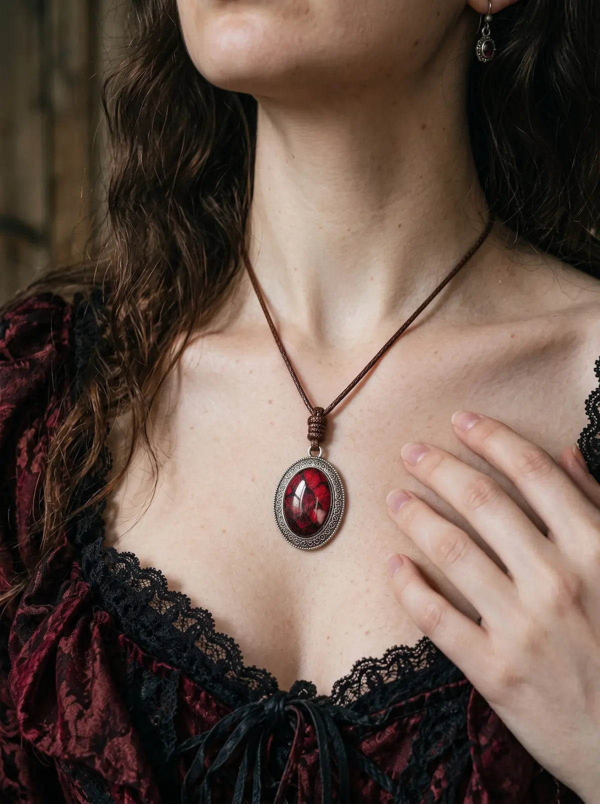 Blood Crimson Eclipse Relic snakeskin pendant worn above a burgundy and black lace neckline