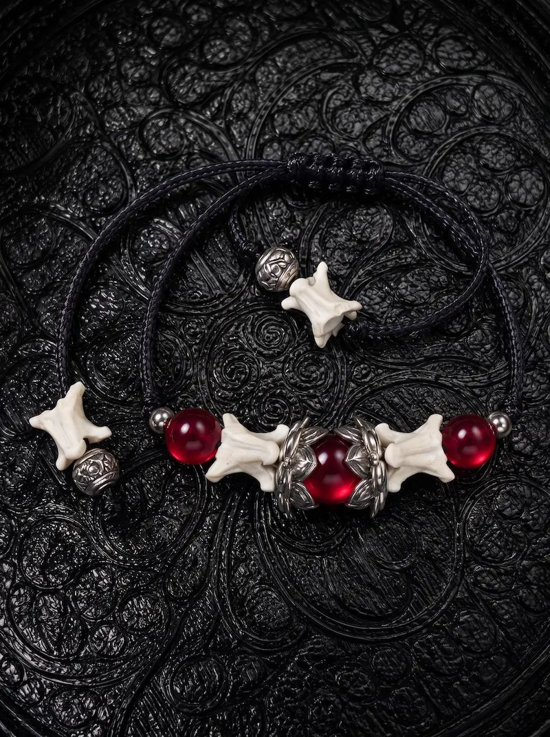Ember Bloom snake bone bracelet with red beads, silver-tone wing accents and bone-tipped black adjustable cords