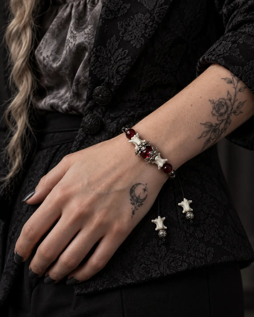 Ember Bloom snake bone bracelet worn on a hand resting against a black patterned jacket
