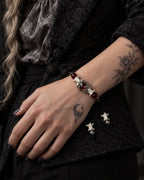 Ember Bloom snake bone bracelet worn on a hand resting against a black patterned jacket