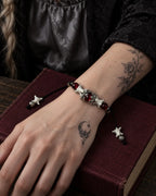 Ember Bloom snake bone bracelet on a wrist resting across a burgundy book on a wooden table