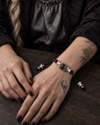 Ember Bloom snake bone bracelet worn with both hands resting on a wooden tabletop