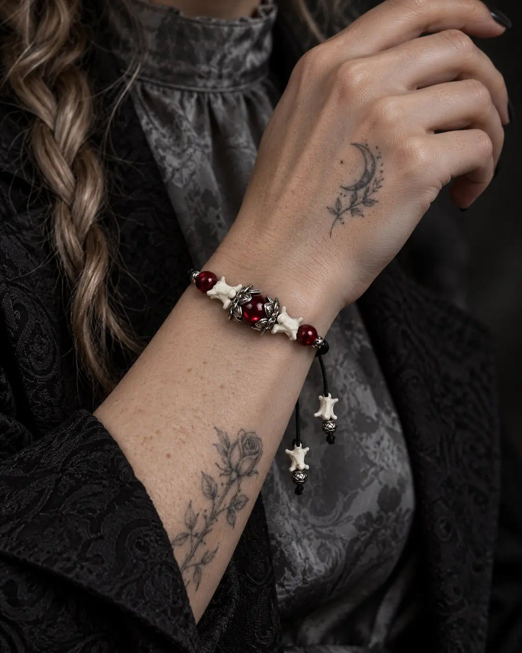 Ember Bloom snake bone bracelet shown on a raised wrist, highlighting the red bead and petal-shaped centerpiece