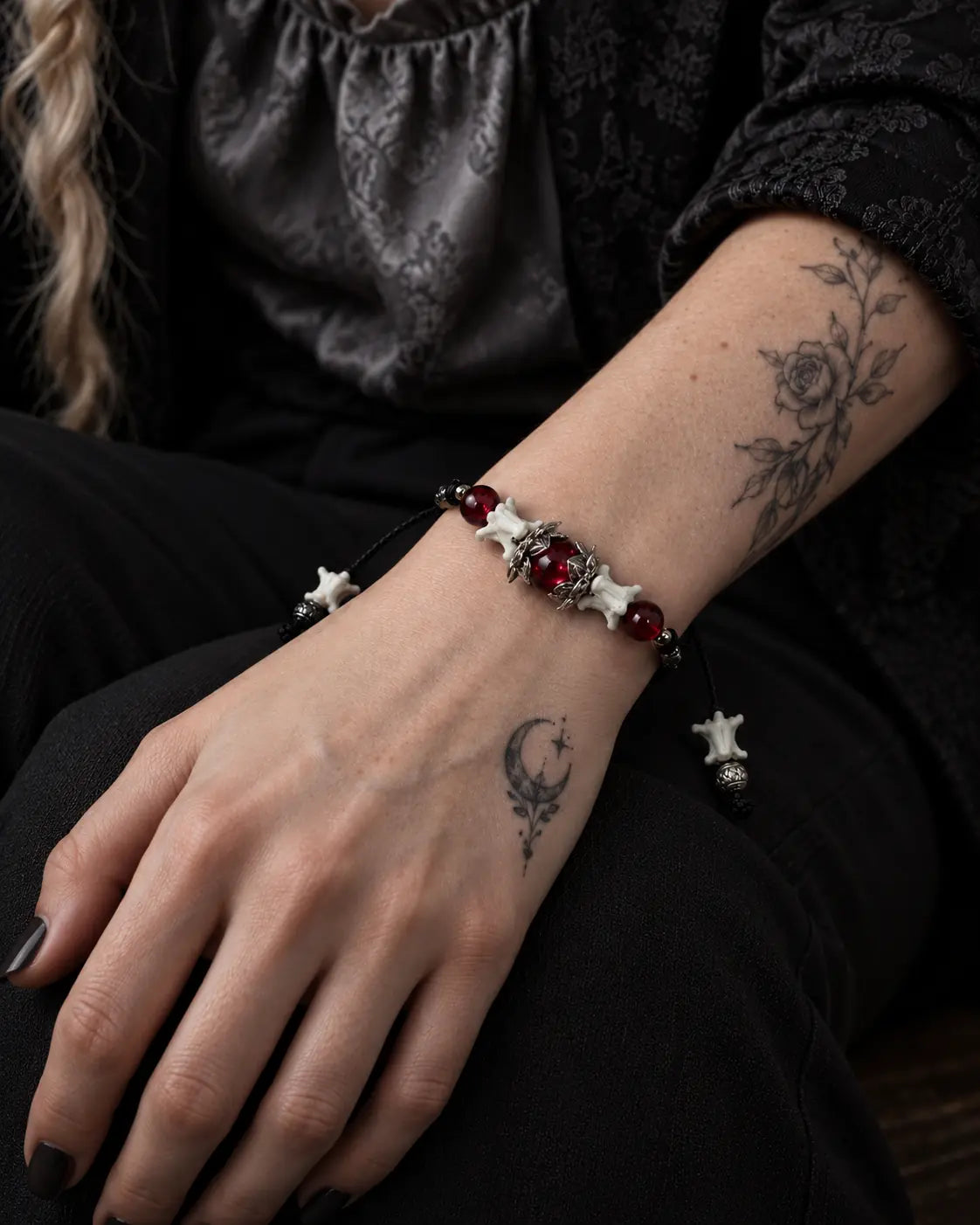 Close-up of the Ember Bloom snake bone bracelet on a hand resting on the thigh