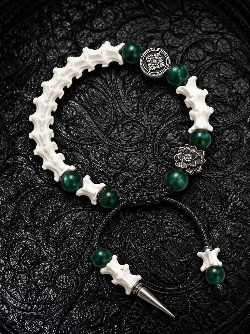 Emerald Thorn snake bone bracelet with green beads, a silver-tone flower, round medallion and pointed metal drop