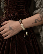 Side view of the Forest Bloom snake bone bracelet across a wrist against a brown velvet dress