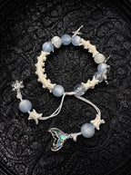 Frost Tide snake bone bracelet with pale blue beads, a snowflake charm and an iridescent tail pendant on white cords