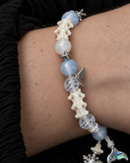 Close-up of the Frost Tide snake bone bracelet showing pale blue and clear beads with silver-tone star and wing accents