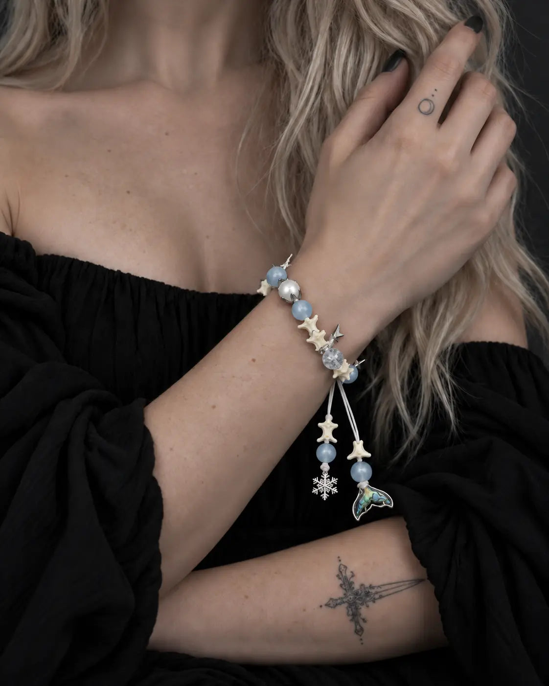 Frost Tide snake bone bracelet worn with the hand near the collarbone above a black neckline