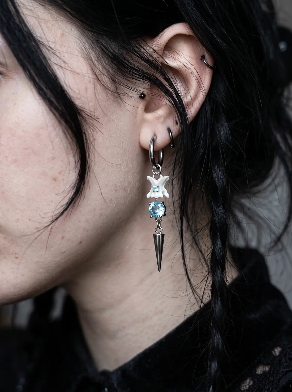 Glacial Spike Snake Bone Earrings, side ear detail showing pale vertebrae, icy bead and star pendant