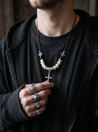 Gravecross Snake Bone Necklace, snake bone cross necklace worn over a dark shirt with silver rings