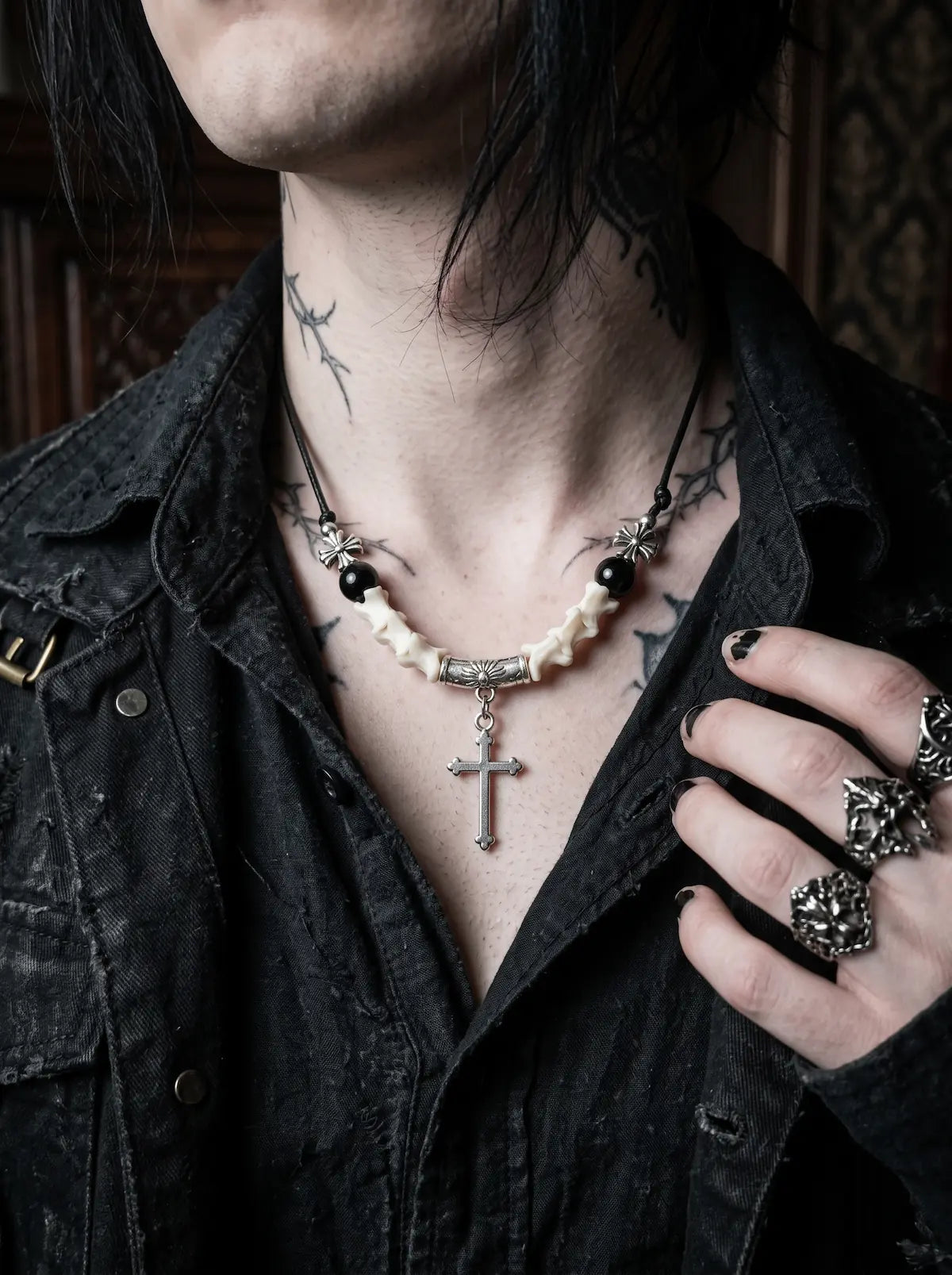 Gravecross Snake Bone Necklace, pale vertebrae necklace with black beads and silver cross on a tattooed model