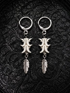 Gravefeather snake bone earrings with engraved silver-tone feather drops, displayed as a pair on black patterned fabric