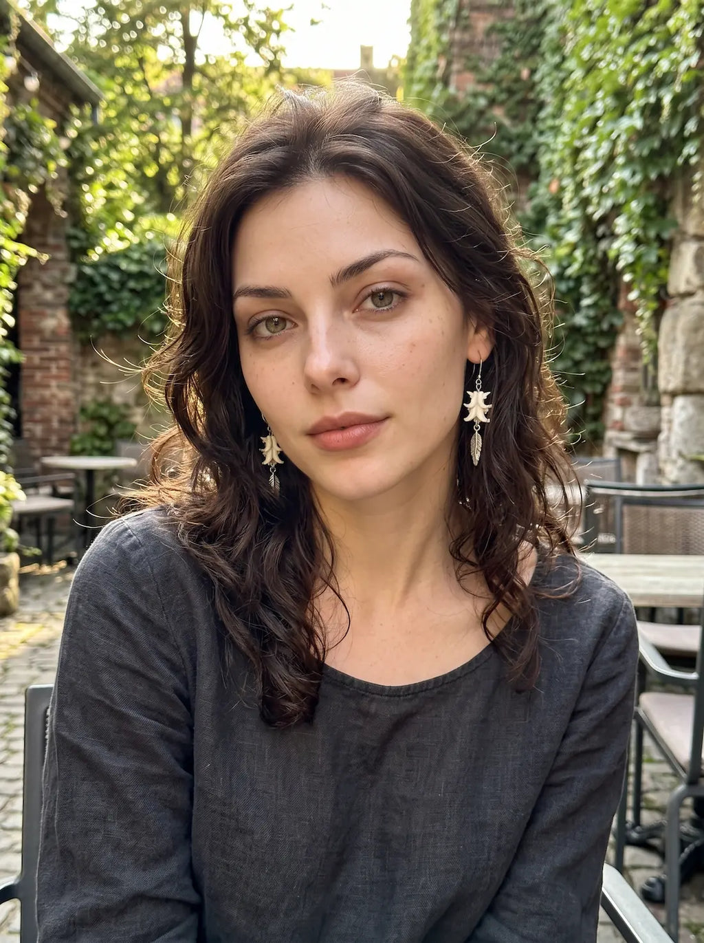 Gravefeather snake bone drop earrings worn as a pair in a front-facing outdoor portrait