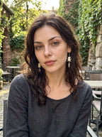 Gravefeather snake bone drop earrings worn as a pair in a front-facing outdoor portrait