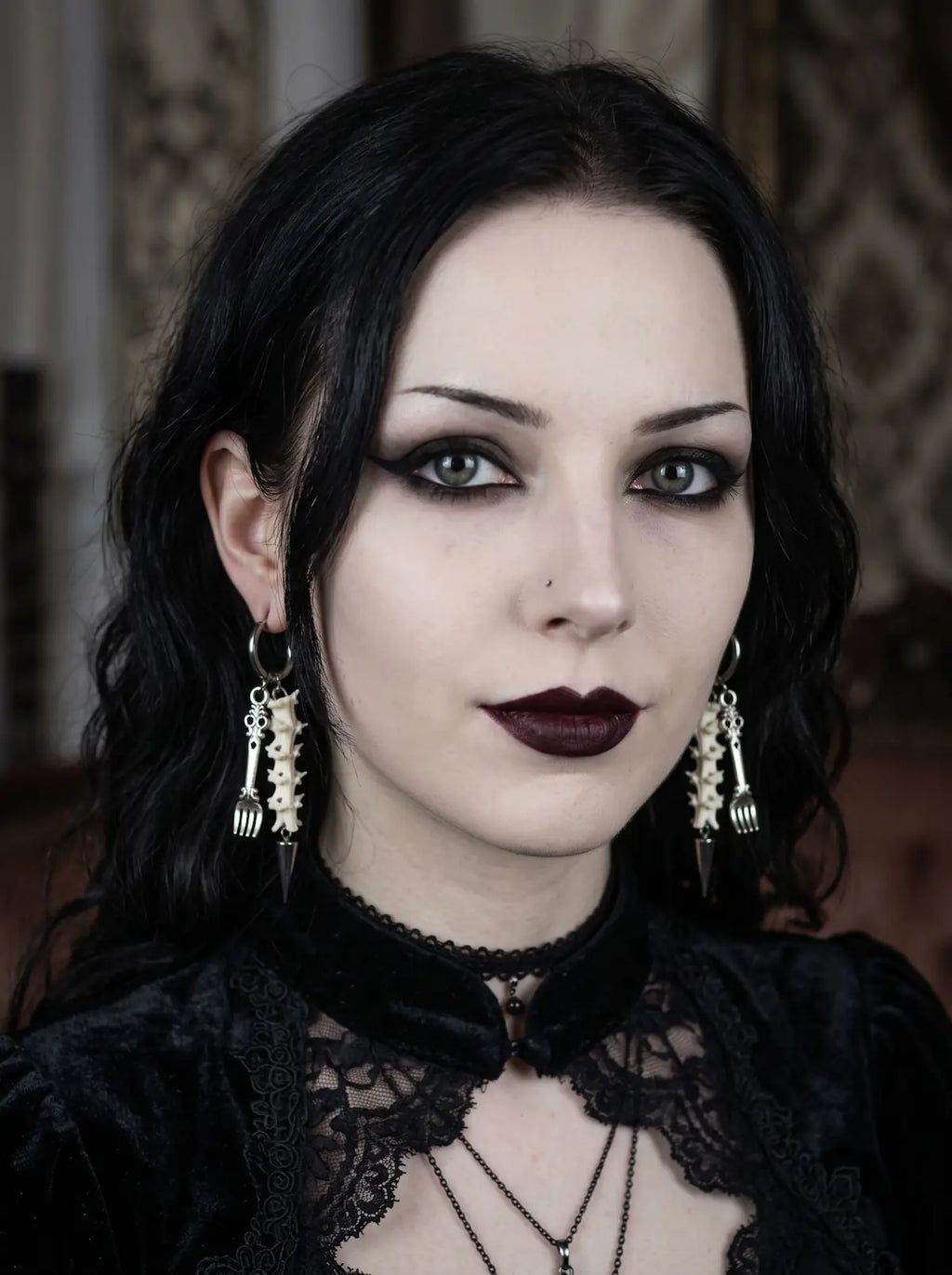 Gravefork Snake Bone Earrings, front portrait wearing the matching pair of vertebrae and metal drop earrings