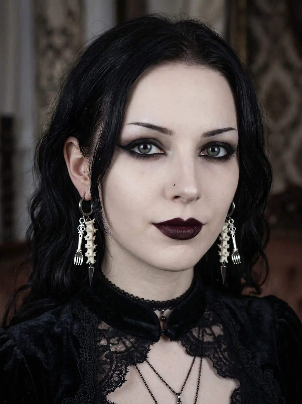 Gravefork Snake Bone Earrings, front portrait wearing the matching pair of vertebrae and metal drop earrings