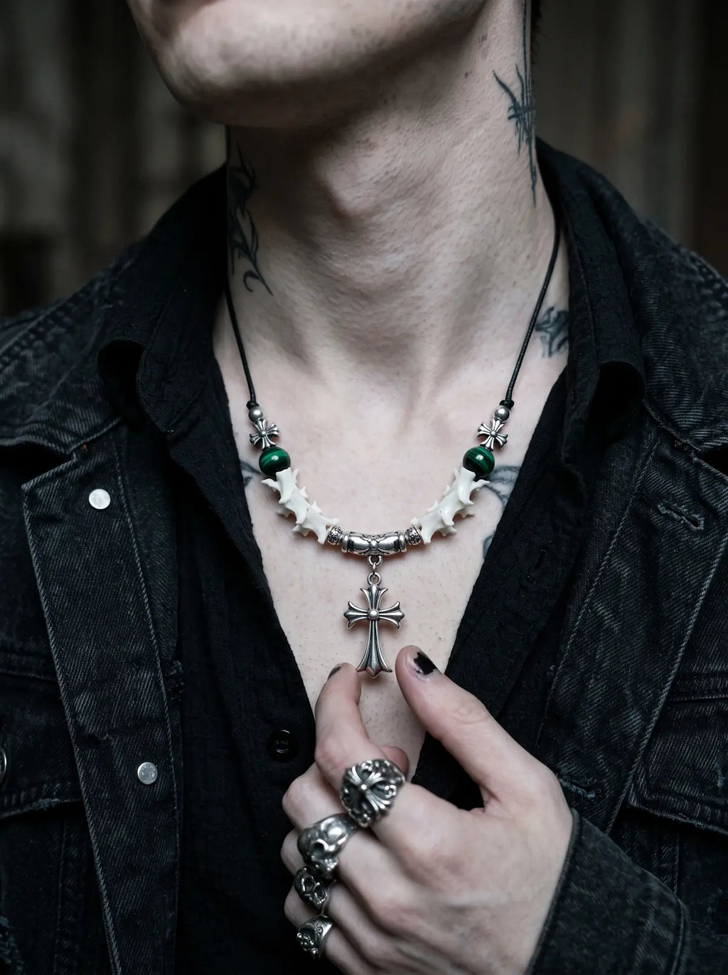 Greenveil Cross Snake Bone Necklace, close chest view of green beads and silver cross necklace against a black jacket