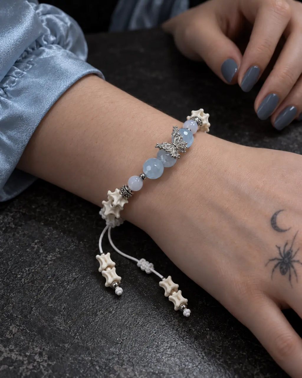 Close-up of the Icewing snake bone bracelet showing its butterfly centerpiece on a wrist resting on a dark table