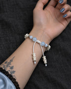 Palm-up view of the Icewing snake bone bracelet showing its white sliding knot and two bone-tipped cords