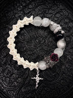 Ivory Thorn Rose snake bone bracelet with pale beads, a dark rose, silver-tone serpent and an ornate cross charm