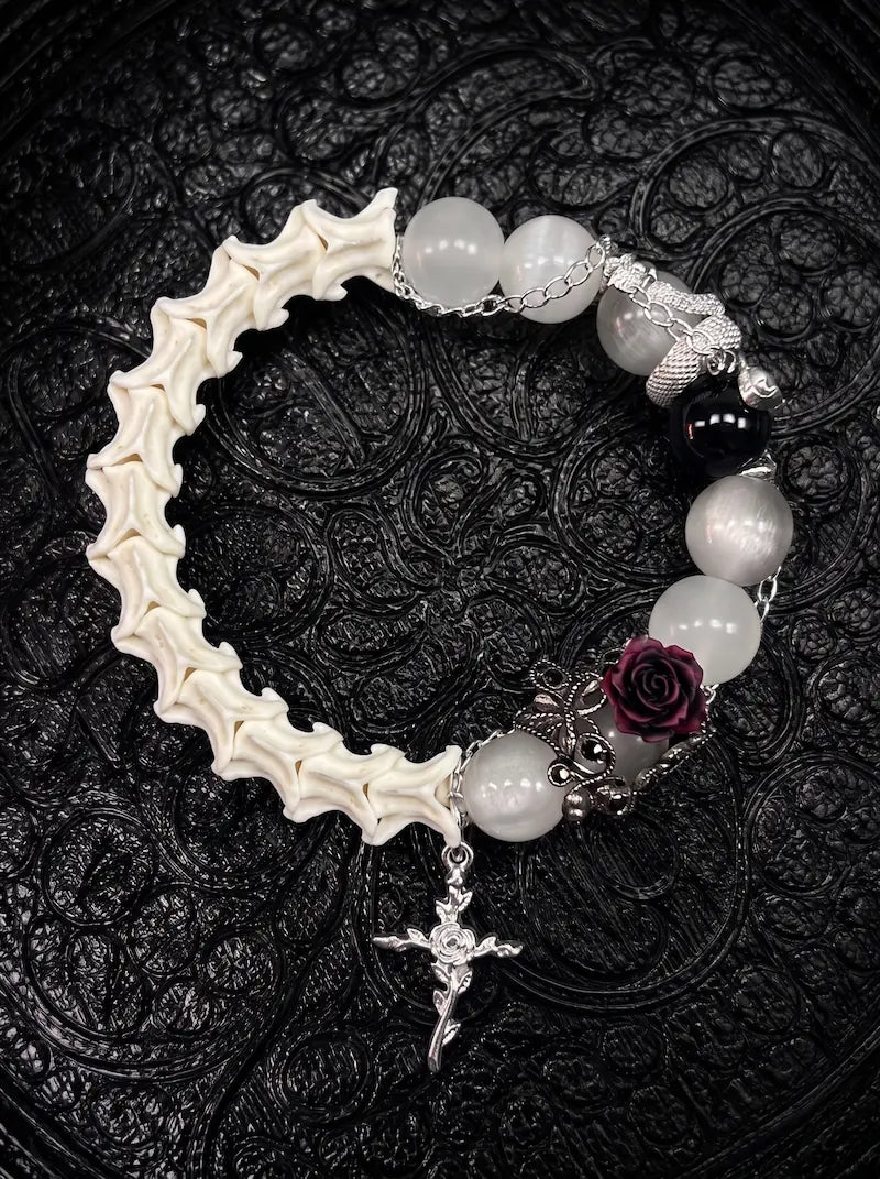 Ivory Thorn Rose snake bone bracelet with pale beads, a dark rose, silver-tone serpent and an ornate cross charm