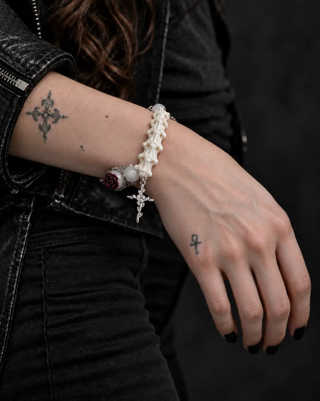 Ivory Thorn Rose snake bone bracelet on a wrist resting across the lap, showing pale beads beside white vertebrae