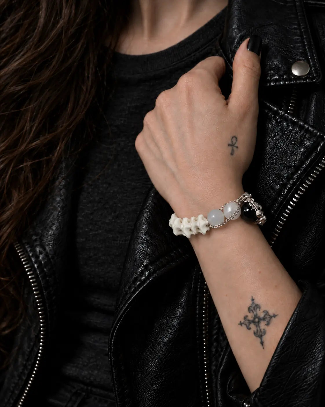 Ivory Thorn Rose snake bone bracelet worn with the hand holding a black leather jacket lapel