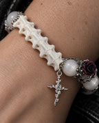 Close-up of the Ivory Thorn Rose snake bone bracelet showing pale beads, a dark rose and its floral cross charm