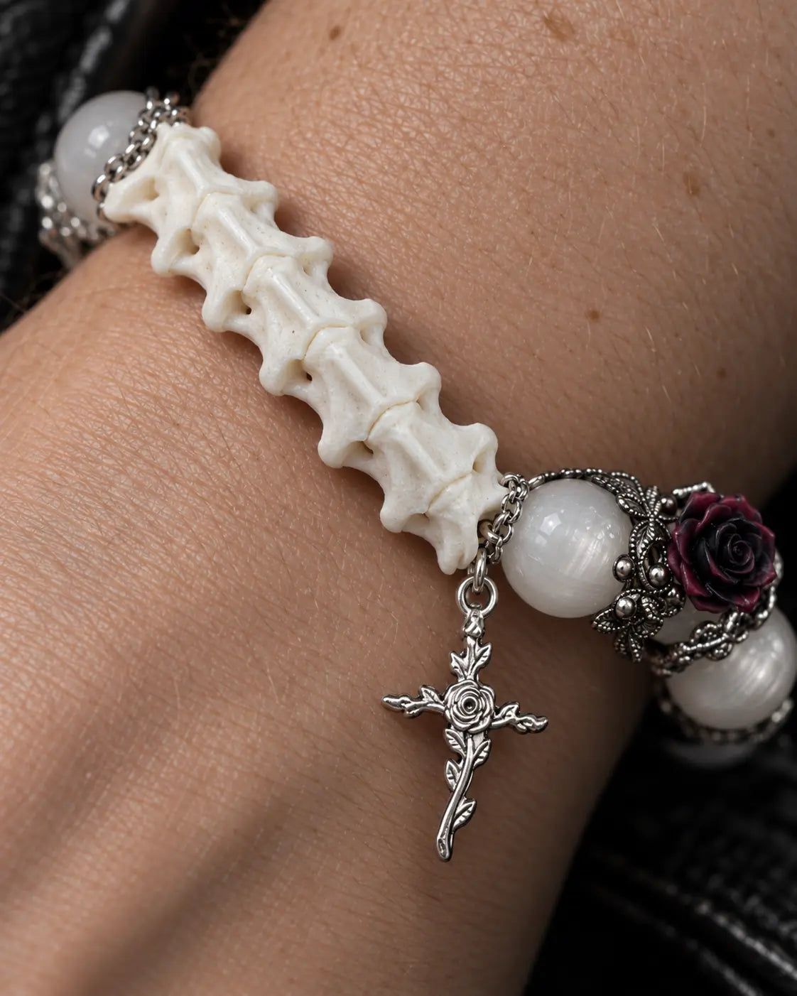 Close-up of the Ivory Thorn Rose snake bone bracelet showing pale beads, a dark rose and its floral cross charm