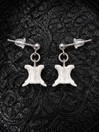 Ivory Vertebra Drop snake bone earrings with silver-tone stud posts and clear backs on black patterned fabric