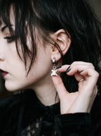 Ivory Vertebra Drop snake bone clip-on earring worn with a finger touching the dangling vertebra