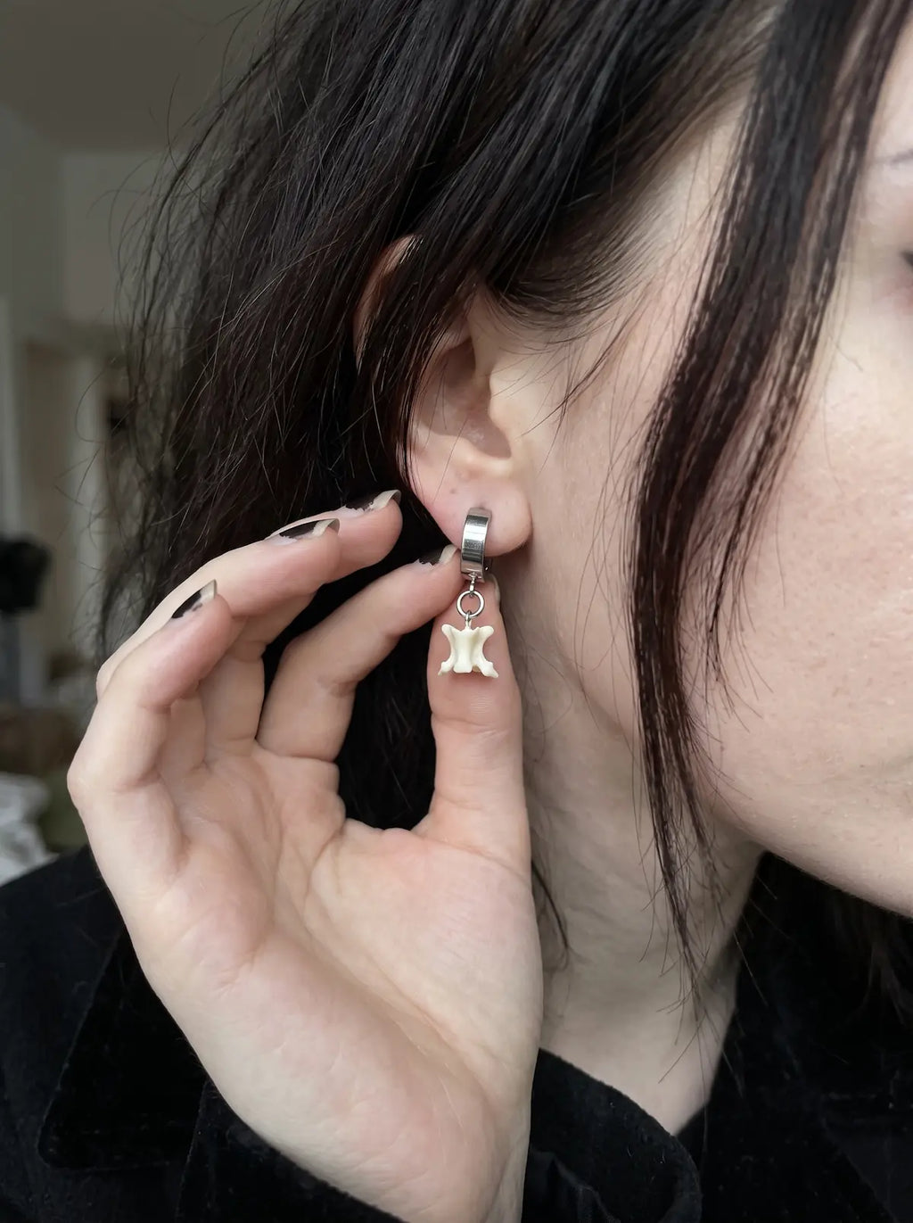 Close-up of the silver-tone clip fitting and white bone on an Ivory Vertebra Drop earring