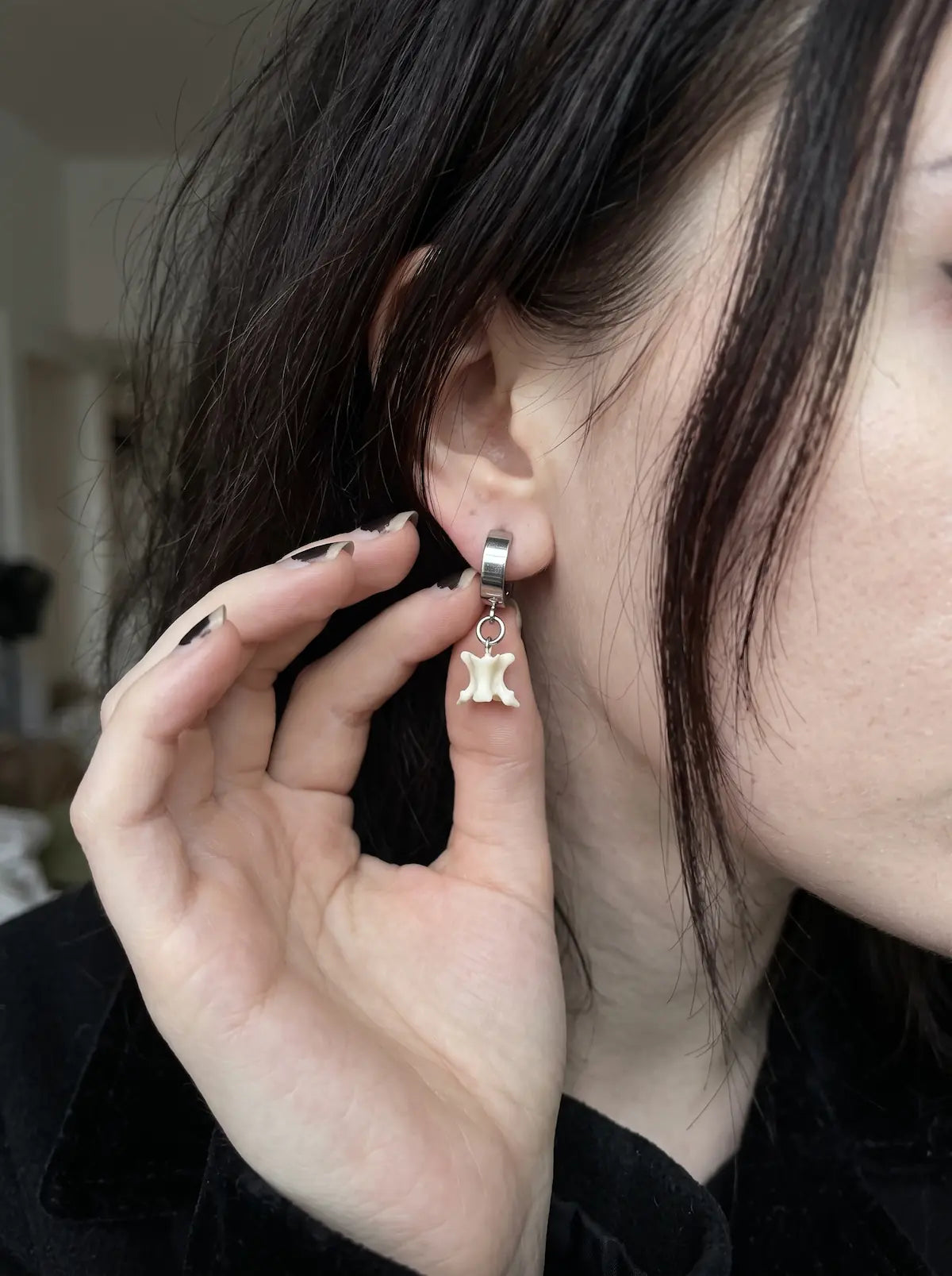 Close-up of the silver-tone clip fitting and white bone on an Ivory Vertebra Drop earring