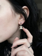 Ivory Vertebra Drop snake bone stud earring shown close to the ear with a fingertip beside the vertebra