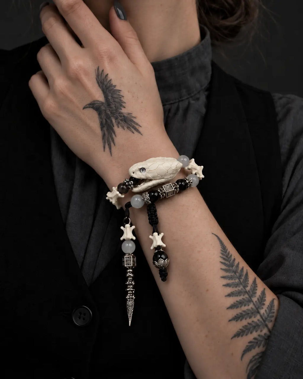 Close-up of the Ivory Serpent Head snake bone bracelet worn with the hand at the neck, highlighting the snake head