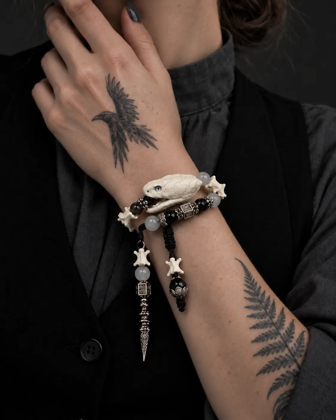 Close-up of the Ivory Serpent Head snake bone bracelet worn with the hand at the neck, highlighting the snake head