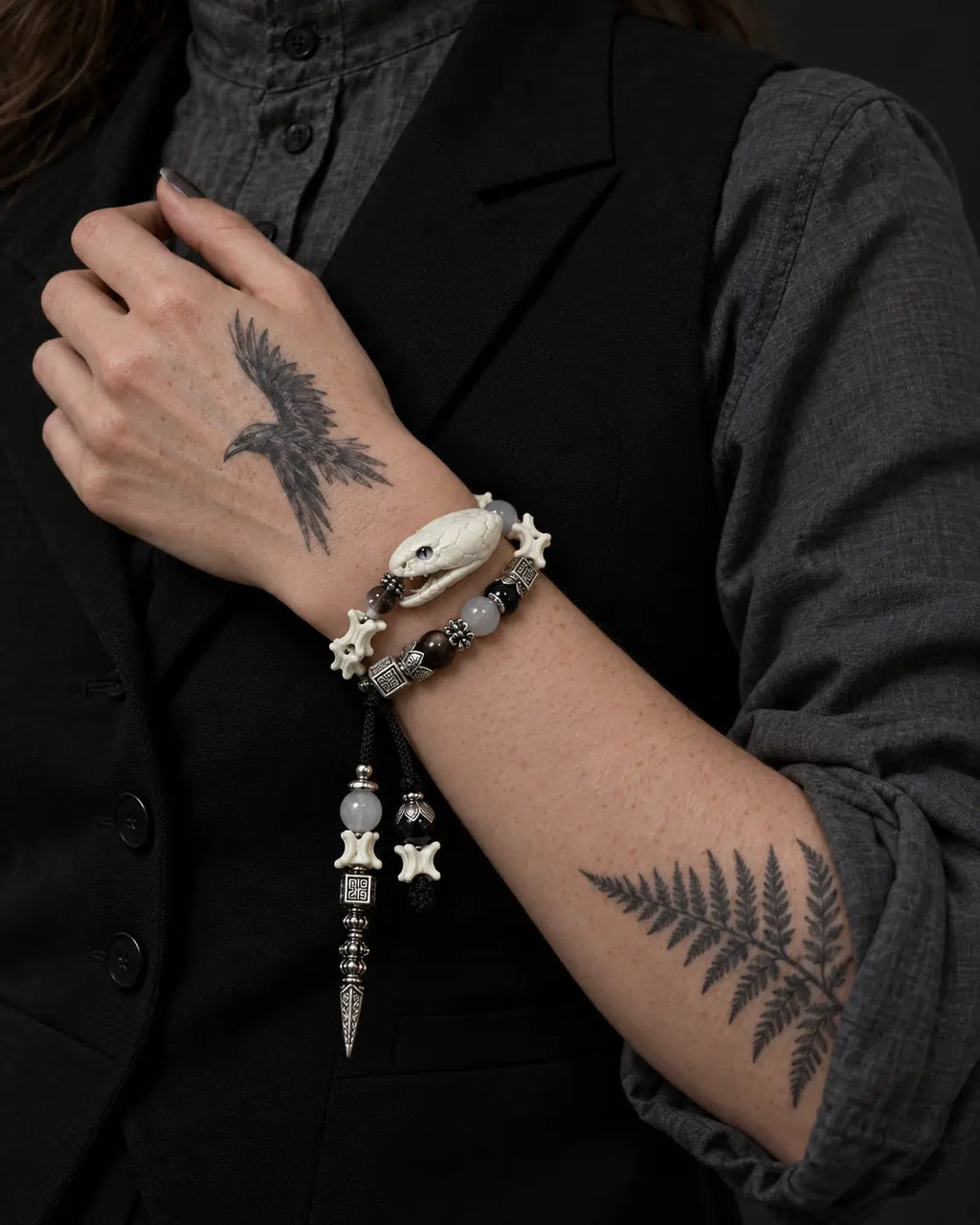 Ivory Serpent Head snake bone bracelet worn in two rows with the hand against a black vest