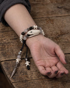 Ivory Serpent Head Snake Bone Bracelet with black and translucent beads and dangling charms, worn on a wrist with the palm facing up.