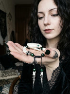 Jadefang Snake Bone Bracelet, pale snake head bracelet held on an open palm with dark metal hanging charms