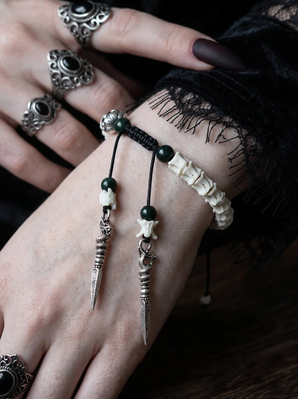 Jadefang Snake Bone Bracelet, close view of snake bone bracelet with green beads and twin pointed metal pendants