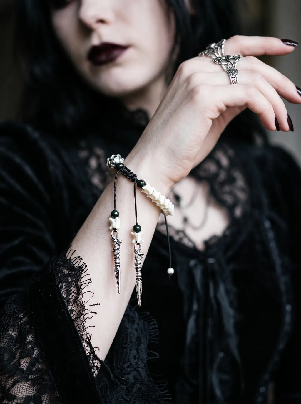 Jadefang Snake Bone Bracelet, Jadefang bracelet worn on a raised wrist, showing its pale head and hanging charms