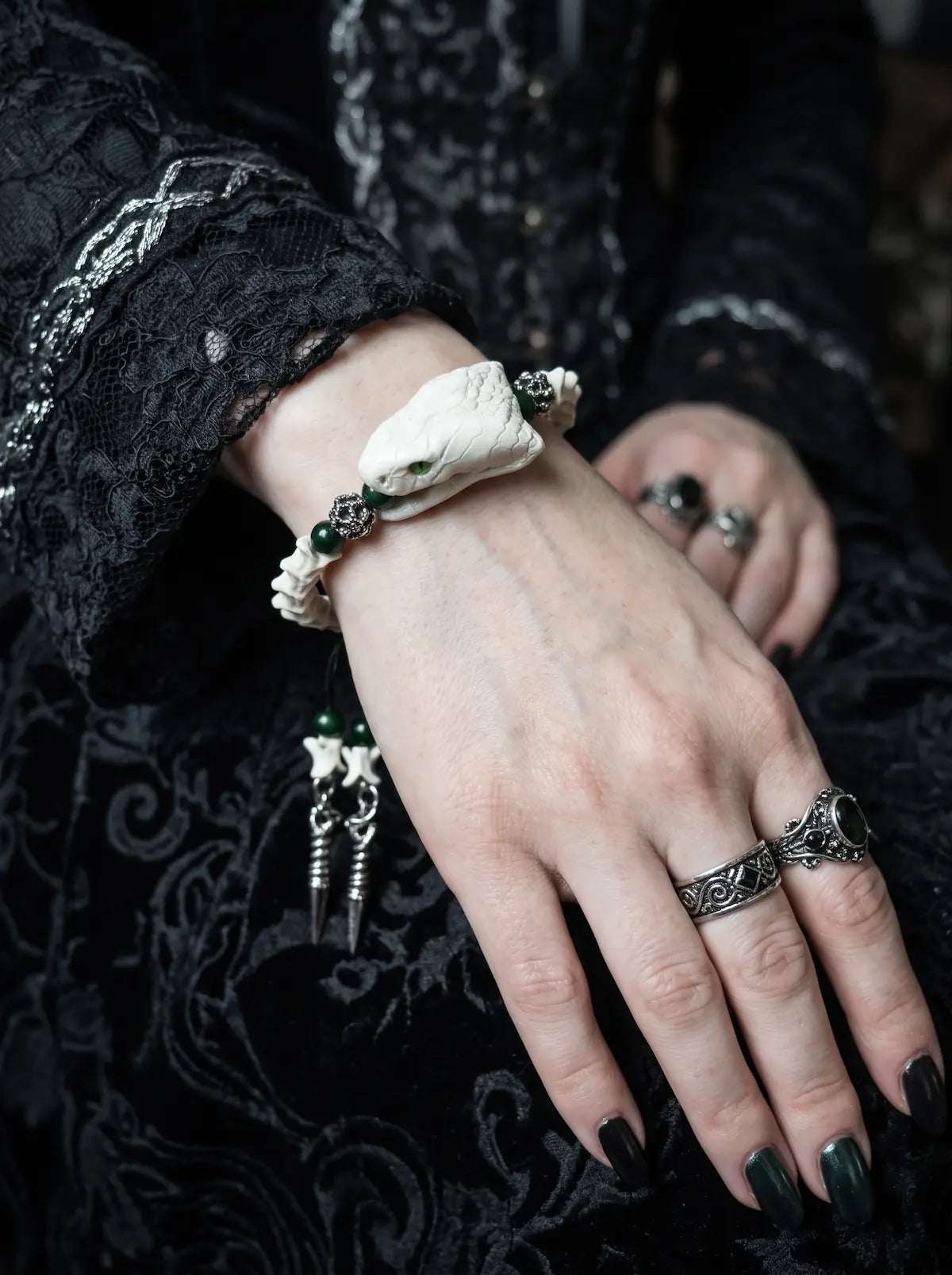Jadefang Snake Bone Bracelet, wrist detail of preserved pale snake head, white vertebrae and green beads