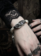 Kingshade Snake Bone Bracelet, raised wrist wearing an ornate dark serpent head and white vertebrae bracelet
