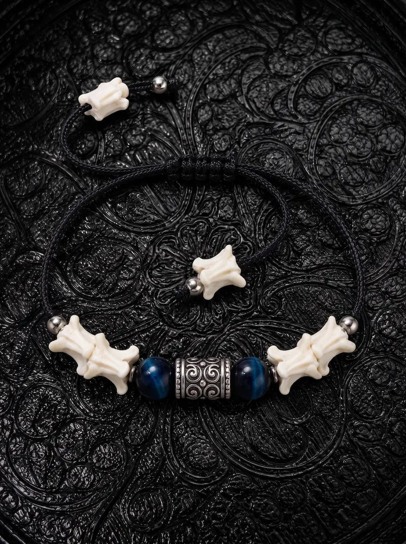 Midnight Blue snake bone bracelet with two deep blue beads, an engraved barrel spacer and bone-tipped black cords