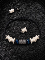 Midnight Blue snake bone bracelet with two deep blue beads, an engraved barrel spacer and bone-tipped black cords