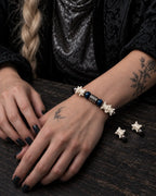 Midnight Blue snake bone bracelet shown with both hands resting on a wooden table