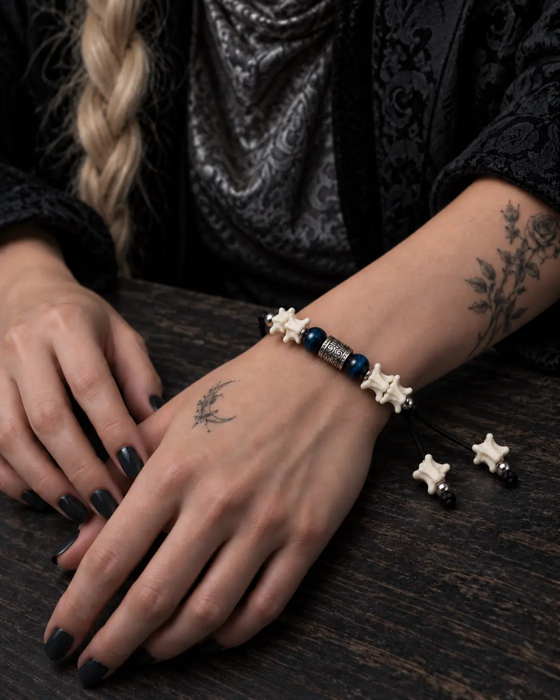 Midnight Blue snake bone bracelet shown with both hands resting on a wooden table