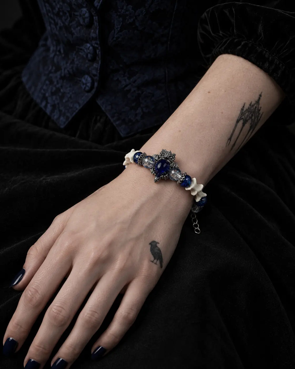 Midnight Guardian snake bone bracelet on a hand resting against black velvet
