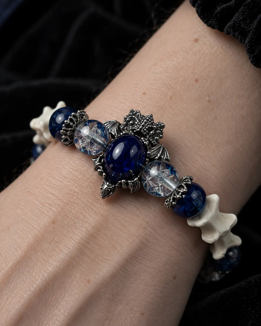 Close-up of the Midnight Guardian snake bone bracelet showing its oval blue centerpiece and clear faceted beads